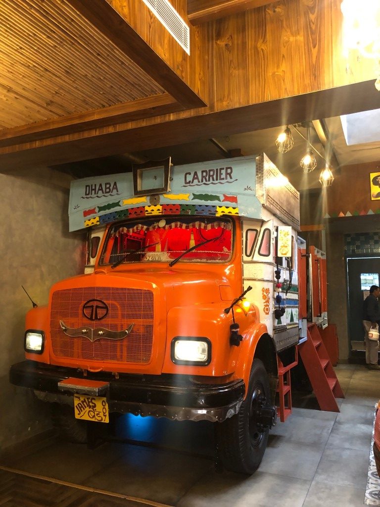 An epic night for the city as Dhaba Estd 1986 Delhi unveils its premier Lounge & Bar: The iconic Dhaba, (Dhaba Estd. 1986 Delhi which grew out of The Claridges hotel on Delhi’s famed Aurangzeb Road), known as the King of Highway Cuisine now gets a whole new avatar as it recreates the same magic again  openingthe doors of its legendary lounge & bar.  Dhaba’s bar ‘Theka’ is not just a bar – it is a complete Theka! Well-stocked with IMFL and imported liquor, it also boasts of signature cocktails - speciality tharras which come in actual Pauva bottles. (Yes, we don’t hold back on anything!) Nestled in Sector 7, DHABA Chandigarh is adorned with new-age fun and kitschy interiors, with the legendary classics on the menu, along with some nouveau beauties - Louder/brasher… you get the drill! The award-winning deliciousness carries forward its thirty-year legacy.  Puneet Gupta, Managing Director, DHABA Chandigarh says, “We are excited to unveil Theka, Dhaba’s premium lounge & bar. The people of Chandigarh are often looking for somewhere to unwind after work. We look forward to indulging our guests with a new dining experience.”  Now managed by Azure Hospitality, the same folks that created Mamagoto, Dhaba is India’s preferred Punjabi Diner. With outlets across the country – walk into any of our signature “colour bomb” spaces and get your dose of the PIND! Rahul Khanna and Kabir Suri, Directors at Azure Hospitality, have played an intrinsic part in developing and managing the company brands, Mamagoto, Dhaba Estd. 1986, Speedy Chow, Rollmaal and recently added brands Sly Granny, Hotel Delmaar and Foxtrot.  With vintage collages and posters, the décor is a nod to the retro India of the 80s and 90s. Striking folksy artwork is displayed on the walls along with signature Dhaba posters completing the eclectic aesthetics. The ambience effortlessly infuses the excitement of a highway meal; and in fact, takes it up a fair few notches! The creative chaos of colours, quirky desi quotes, revival of vintage black and white Bollywood posters and the signature truck art adds to the overall dining experience. The outdoor area is the highlight of the restaurant which is designed like an Akhaada for Pehelwans or a wrestler’s den as seen in the villages in North India. The mood of the restaurant is further enhanced by the mock façade of a building, which is designed like a small town. But the real highway magic takes place in the kitchen which carries the legacy of over 30 years. Chef Shamshool expertly helms the Dhaba kitchen narrative, recreating its legendary signature recipes bringing forth the best of highway cuisine and North Indian cuisine concepts. With signature Recipes Since 1986 and the new experimental Highway Specials, there are a whole lot of new and signature dishes for everyone to try.  The food menu is inspired by travels down the highways of India and the eccentric by-lanes of old towns famous for unique age-old recipes. In addition to the classics, the menu experiments with newer flavours showcasing Highway specials, not only from Punjab but from all over the country. The essence and soul of Dhaba is Punjabi, however a whole range of regional dishes are now available for indulgence.  A meal here is rounded off with Desi Paan available in all sorts of flavours – Nutella, Thanda Thanda; go crazy! We’ve also given our interior designers a license to go nuts - vintage Bollywood posters, rustic interiors, truck art elements and an actual truck that you can enjoy your meal on – all enhanced with the masala of Bollywood music – LOUD Bollywood music. And if you stick around long enough, you may also witness the staff breaking into a dance when the song of the month comes on! If you’re on a diet – leave this site now ;)